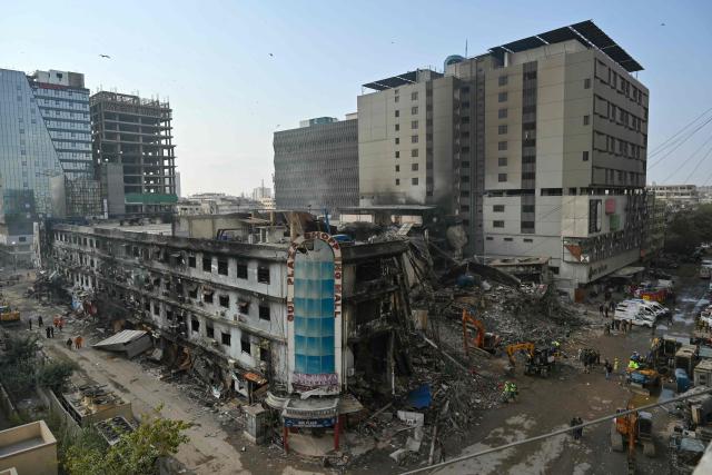Workers clear debris after a massive fire broke out at a shopping mall in Karachi on January 22, 2026. The death toll from a mall fire in Pakistan's biggest city rose to at least 55 people, a Karachi government official told AFP on January 22. (Photo by Asif HASSAN / AFP)