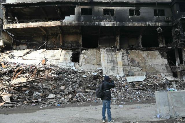 A photographer takes pictures of a charred shopping mall in Karachi on January 22, 2026, after a massive fire broke out on January 17. The death toll from a mall fire in Pakistan's biggest city rose to at least 55 people, a Karachi government official told AFP on January 22. (Photo by Asif HASSAN / AFP)