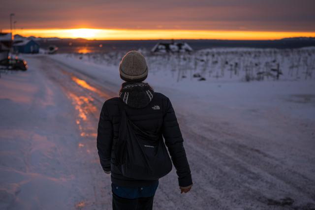 A person walks along an icy road reflecting the light of the setting sun in Nuuk, Greenland, on January 21, 2026. The US President will show off his new "Board of Peace" at Davos on January 22, 2026, burnishing his claim to be a peacemaker a day after backing off his own threats against Greenland. (Photo by Jonathan NACKSTRAND / AFP)