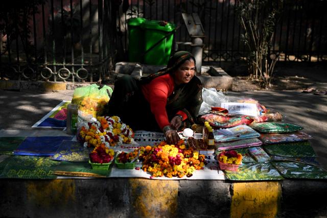 A vendor sells religious offerings near a grave in New Delhi on January 22, 2026. (Photo by Sajjad HUSSAIN / AFP)