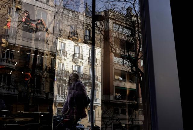 A picture taken on January 20, 2026 shows a woman reflected in a shop window in the Ortega y Gasset street in Madrid. Madrid has emerged as a coveted global luxury housing destination as Latin American and US investors fuel a real estate boom, seduced by competitive prices and high living standards. (Photo by OSCAR DEL POZO / AFP)