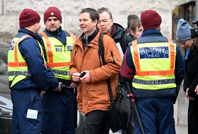 Wolfram Jarosch (3rd L), father of the arrested German anti-fascist activist Maja T, walks past Hungarian policemen after talking to journalists close to the building where is being held the trial against Maja T in Budapest on January 22, 2026. The Hungarian public prosecutor's office accuses Maja T of being involved in attacks against right-wing extremists in Budapest in February 2023. (Photo by Attila KISBENEDEK / AFP)