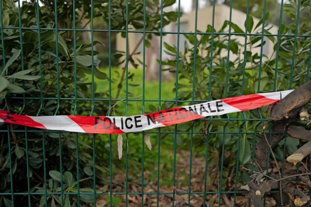 This photograph shows a French Police tape set by a traffic lampost bent by the car of a woman murdered while driving with her baby in Nice, southeastern France, on January 22, 2026. The tragedy took place on January 21, 226 shortly after 6 pm at an intersection near a high school in the west of the city. A man on a scooter pulled up alongside the driver and fired about ten shots at point-blank range through the vehicle's window, Nice prosecutor said in a statement. (Photo by Valery HACHE / AFP)