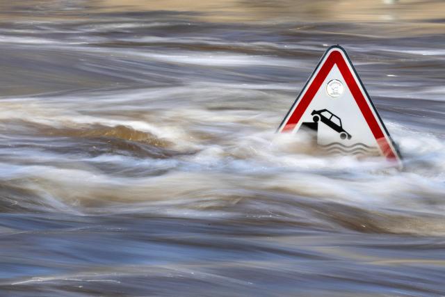 This photograph shows a road sign in a flooded street in Quimperle, western France on January 22, 2026. Finistиre and Morbihan departments of western France are on orange alert on January 21, 2026, for “rain and flooding”. (Photo by Fred TANNEAU / AFP)
