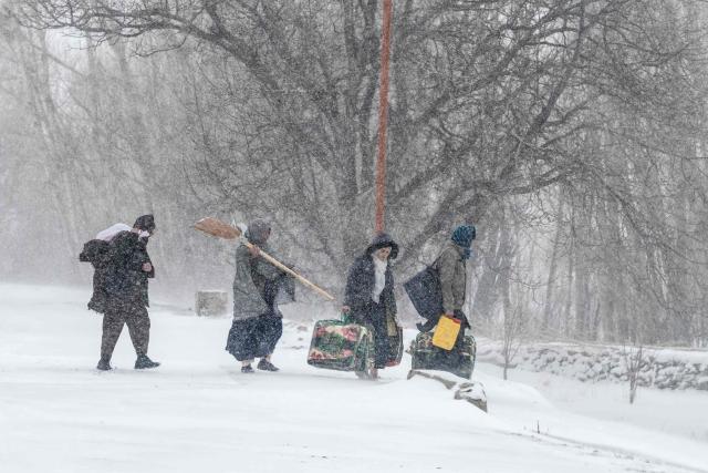 People with their belongings walk along a road during snowfall in Shibar area of the Sheikh Ali district of Afghanistan's Parwan province on January 21, 2026. (Photo by Wakil KOHSAR / AFP)