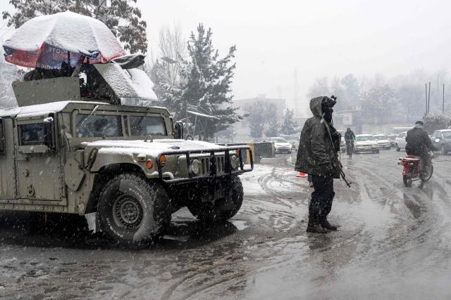 A Taliban security personnel stands guard at a checkpoint during snowfall in Kabul on January 22, 2026. Severe storms and a rain-triggered landslide have killed at least nine children across southern and eastern Afghanistan, officials said, with residents facing further risks as heavy snow hits the country. (Photo by Wakil KOHSAR / AFP)