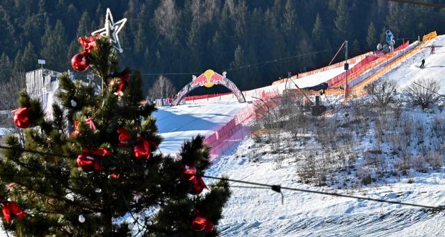 The ski slope with the "Red Bull jump" at the famous "Streif" (Hahnenkamm downhill course) is seen behind a Christmas tree at the ski resort of Kitzbuehel, Austria on a free day of the Men's FIS Alpine Skiing World Cup Austria on January 22, 2026. (Photo by Joe Klamar / AFP)