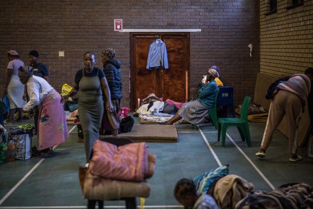 Displaced families from the informal settlement of Sporong by the ongoing unrest between the community and  a group of artisanal miners commonly referred to as "zama zamas", tidy up their spaces at the Randgate Community Hall in Randfontein, on January 22, 2026 where the displaced took refuge. Residents and local officials blame artisanal miners, long associated with sudden eruptions of violence, running gun battles and the shadowy networks that sustain South Africa's illicit gold trade. 
Known locally as "zama zamas" -- "those who try" in the Zulu language -- they have become an entrenched presence in the shantytowns that ring Johannesburg and its satellite settlements along the gold reef. (Photo by MARCO LONGARI / AFP)