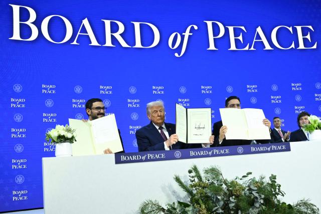 Bahrein's Minister of the Prime Minister's court Sheikh Isa bin Salman bin Hamad al-Khalifa (L), US President Donald Trump (C) and Morocco's Foreign Minister Nasser Bourita hold a signed founding charter at the "Board of Peace" meeting during the World Economic Forum (WEF) annual meeting in Davos on January 22, 2026. US President Donald Trump will show off his new "Board of Peace" at Davos on January 22, 2026 burnishing his claim to be a peacemaker a day after backing off his own threats against Greenland. Originally meant to oversee the rebuilding of Gaza after the war between Hamas and Israel, the board's charter does not limit its role to the Strip, and has sparked concerns that Trump wants it to rival the United Nations. (Photo by Mandel NGAN / AFP)