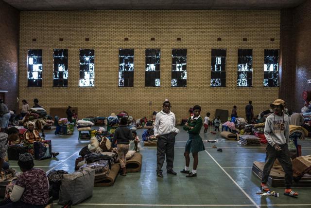 Schoolchildren, displaced from the informal settlement of Sporong by the ongoing unrest between the community and  a group of artisanal miners commonly referred to as "zama zamas", stand at the Randgate Community Hall in Randfontein, on January 22, 2026 where the displaced took refuge. Residents and local officials blame artisanal miners, long associated with sudden eruptions of violence, running gun battles and the shadowy networks that sustain South Africa's illicit gold trade. 
Known locally as "zama zamas" -- "those who try" in the Zulu language -- they have become an entrenched presence in the shantytowns that ring Johannesburg and its satellite settlements along the gold reef. (Photo by MARCO LONGARI / AFP)