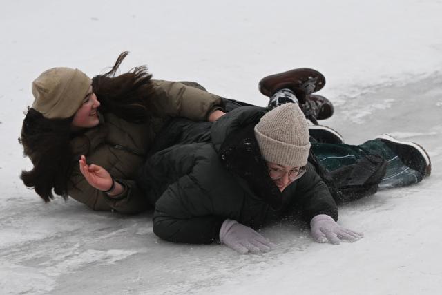 Schoolchildren sled down the slope during an air raid alert in a park in Kyiv on January 22, 2026, amid the Russian invasion of Ukraine. Schools in Ukraine's capital remain closed until February due to Russian strikes battered the energy sector amid below-freezing temperatures. (Photo by Sergei GAPON / AFP)