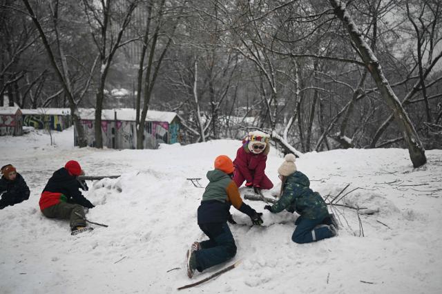 Children play on a pile of snow in a park in Kyiv on January 22, 2026, amid the Russian invasion of Ukraine. Schools in Ukraine's capital remain closed until February due to Russian strikes battered the energy sector amid below-freezing temperatures. (Photo by Sergei GAPON / AFP)
