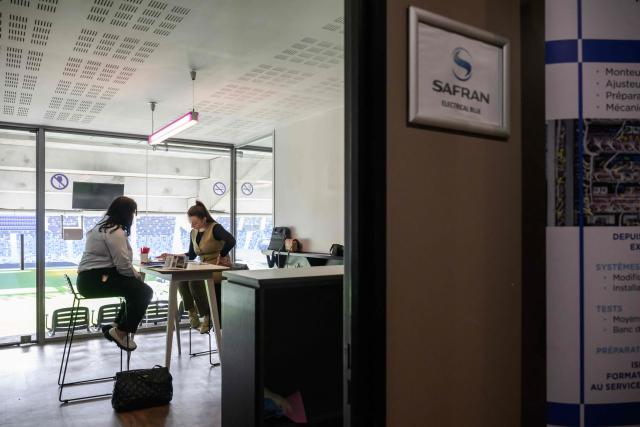 A Safran aerospace representative speaks with an attendee at a booth at an 'AeroDay' recruitment event organized by the Randstad Group, at the Stadium de Toulouse in Toulouse, southwestern France on January 22, 2026. According to organizers, some 2,800 positions are to be filled across the French aeronautics, defense and space industry sectors. (Photo by Ed JONES / AFP)