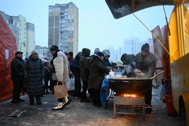 Volunteers of the US-based food charity World Central Kitchen distribute hot meal to local residents in a residential area of Kyiv that has been left without electricity and water due to recent Russian strikes battering the energy sector on January 22, 2026, amid the Russian invasion of Ukraine.  (Photo by Sergei GAPON / AFP)