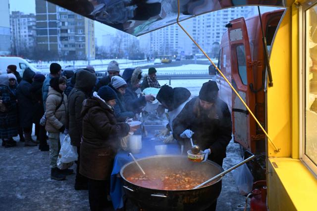 Volunteers of the US-based food charity World Central Kitchen distribute hot meal to local residents in a residential area of Kyiv that has been left without electricity and water due to recent Russian strikes battering the energy sector on January 22, 2026, amid the Russian invasion of Ukraine.  (Photo by Sergei GAPON / AFP)
