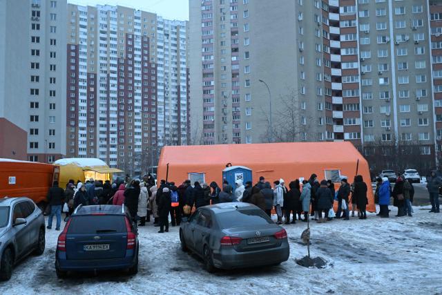 Local residents queue to receive hot meal distributed by volunteers of the US-based food charity World Central Kitchen in a residential area of Kyiv that has been left without electricity and water due to recent Russian strikes battering the energy sector on January 22, 2026, amid the Russian invasion of Ukraine. (Photo by Sergei GAPON / AFP)