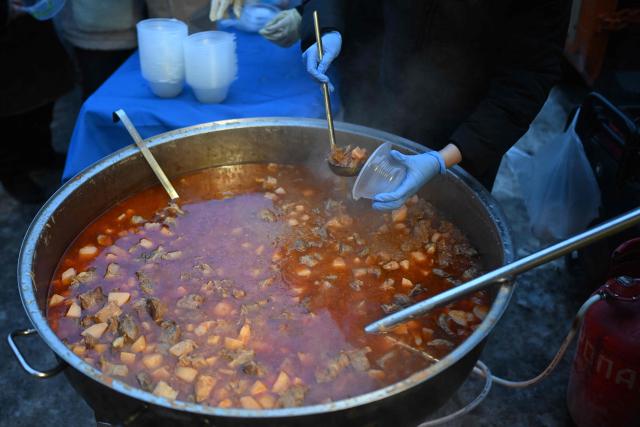 A volunteer of the US-based food charity World Central Kitchen distributes hot meal to local residents in a residential area of Kyiv that has been left without electricity and water due to recent Russian strikes battereing the energy sector on January 22, 2026, amid the Russian invasion of Ukraine.  (Photo by Sergei GAPON / AFP)
