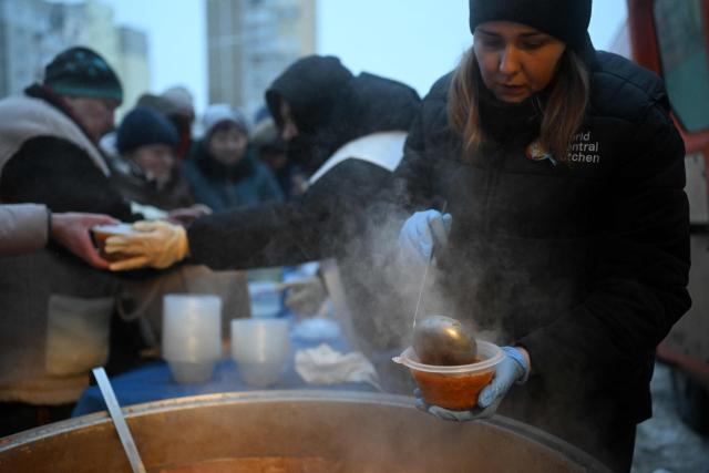 Volunteers of the US-based food charity World Central Kitchen distribute hot meal to local residents in a residential area of Kyiv that has been left without electricity and water due to recent Russian strikes battering the energy sector on January 22, 2026, amid the Russian invasion of Ukraine.  (Photo by Sergei GAPON / AFP)