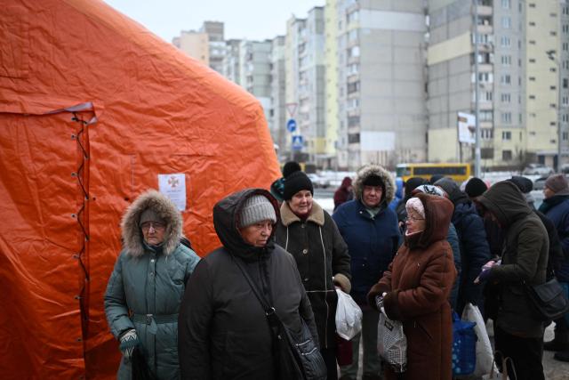TOPSHOT - Local residents gather to receive hot meal distributed by volunteers of the US-based food charity World Central Kitchen in a residential area of Kyiv that has been left without electricity and water due to recent Russian strikes battering the energy sector on January 22, 2026, amid the Russian invasion of Ukraine.  (Photo by Sergei GAPON / AFP)