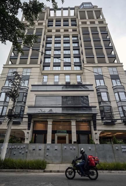 A motorbiker rides past the Banco Master building protected by hoardings and with the bank's logo covered in plastic, in Sao Paulo, Brazil, on January 22, 2026, after Brazil's Central Bank ordered its shutdown due to a major liquidity crunch and "serious violations" of financial regulations. (Photo by NELSON ALMEIDA / AFP)