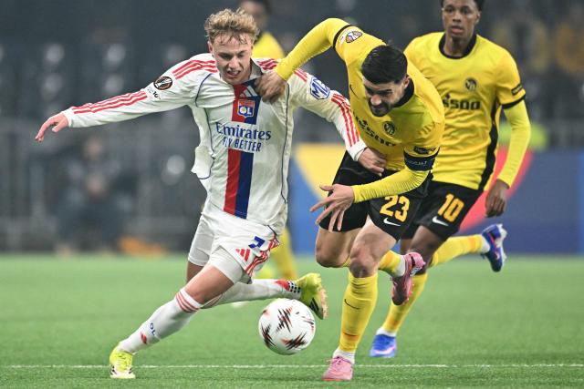 Lyon's Czech forward #07 Adam Karabec (L) and Young Boys' Swiss defender #23 Loris Benito (C) fight for the ball during the UEFA Europa League, league phase, football match between Young Boys and Olympique Lyonnais (OL) at the Wankdorf stadium in Bern on January 22, 2026. (Photo by Sébastien BOZON / AFP)