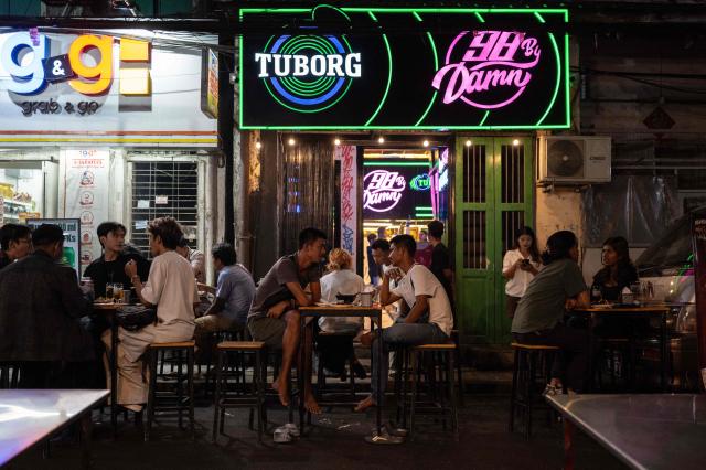 People sit at an outside bar in Yangon, Myanmar, on January 22, 2026. (Photo by ANTHONY WALLACE / AFP)