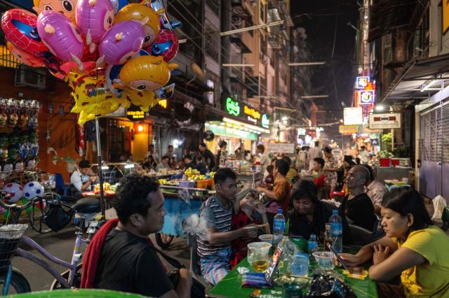 People eat at a street restaurant in Yangon, Myanmar, on January 22, 2026. (Photo by ANTHONY WALLACE / AFP)
