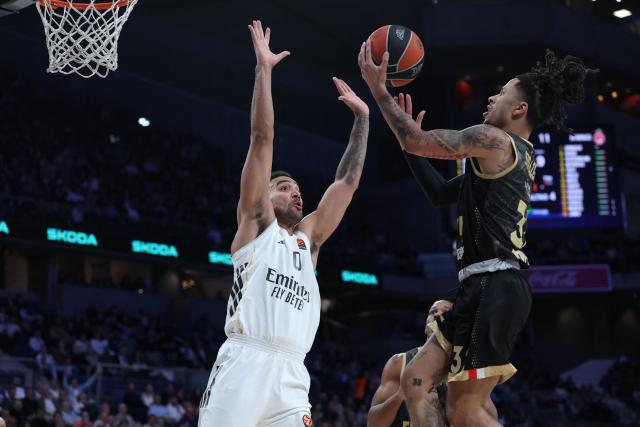 AS Monaco's French centre #32 Matthew Strazel attempts a shot in spite of Real Madrid's Canadian forward #00 Trey Lyles during the Euroleague basketball match between Real Madrid Baloncesto and Monaco at Movistar Arena in Madrid on January 22, 2026. (Photo by Thomas COEX / AFP)