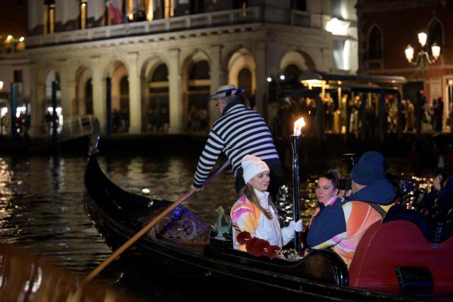 A torchbearer carries the Olympic flame on a gondola in Venice during the Torch Relay to Milano Cortina 2026 Olympic Games, on January 22, 2026. (Photo by ANDREA PATTARO / AFP)
