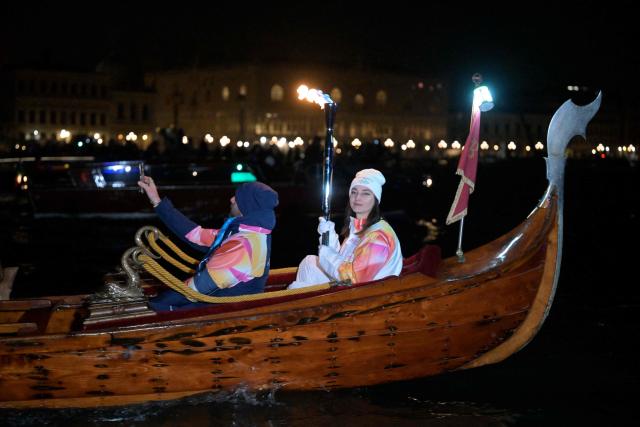 A torchbearer carries the Olympic flame on a gondola in Venice during the Torch Relay to Milano Cortina 2026 Olympic Games, on January 22, 2026. (Photo by ANDREA PATTARO / AFP)