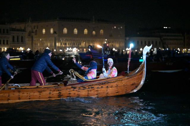 A torchbearer carries the Olympic flame on a gondola in Venice during the Torch Relay to Milano Cortina 2026 Olympic Games, on January 22, 2026. (Photo by ANDREA PATTARO / AFP)