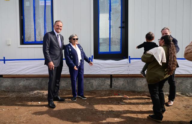 Real Estate developer Rick Caruso stands beside homeowner Rosalina Rodriguez as family members view their first free Modular Home put in place in Altadena, California on January 22, 2025, over a year after the fire destroyed some 9,400 structures. As part of its recovery efforts, the nonprofit coalition Steadfast LA has partnered with Samara, a modular house builder company, to provide homes at no cost to low-income Altadena and Pacific Palisades homeowners who lost their primary residences during the Eaton and Palisades wildfires of January 2025. The Rodriguez family is the recipient of the first free modular home. (Photo by Frederic J. BROWN / AFP)