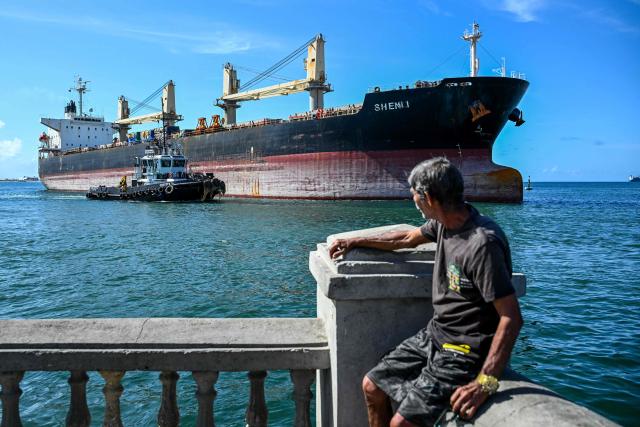 A man looks at the bulk carrier Shenli, sailing under the flag of Panama, in Puerto Cabello, Carabobo state, Venezuela, on January 22, 2026. (Photo by Ronaldo SCHEMIDT / AFP)