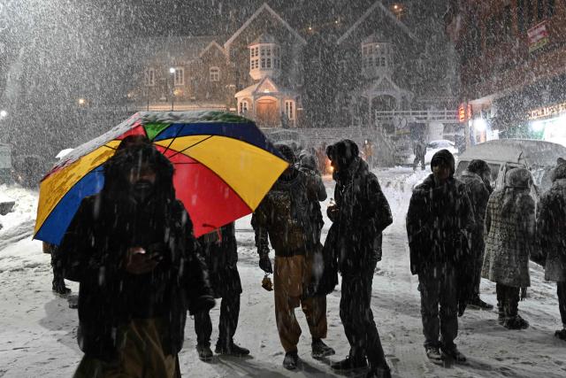 Tourist gather during a snowfall in Murree, some 60 km north of Islamabad on January 23, 2026. (Photo by Aamir QURESHI / AFP)