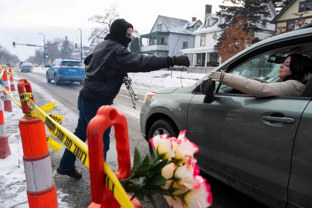 A man hands out whistles to people in cars passing by the memorial for Renee Nicole Good, in Minneapolis, Minnesota, on January 22, 2026. Residents of the city have taken to blowing whistles every time they spot ICE agents in the streets of the city. (Photo by ROBERTO SCHMIDT / AFP)