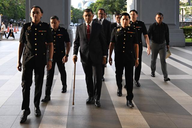 Former Malaysia's armed forces chief Nizam Jaffar (C) is escorted by Malaysian Anti-Corruption Commission (MACC) officers to a special court in Kuala Lumpur on January 23, 2026. (Photo by Mohd RASFAN / AFP)