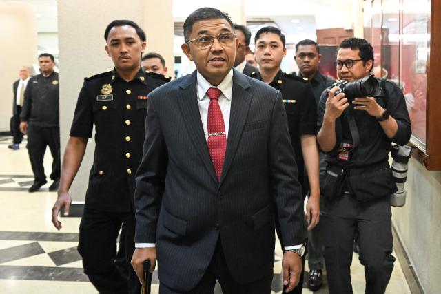 Former Malaysia's armed forces chief Nizam Jaffar (C) is escorted by Malaysian Anti-Corruption Commission (MACC) officers to a special court in Kuala Lumpur on January 23, 2026. (Photo by Mohd RASFAN / AFP)