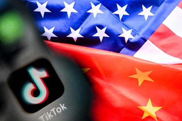 (FILES) A photo taken on April 10, 2025 shows the Chinese social networking service TikTok's logo on a smartphone screen (L) and a US and China flag illustration on a laptop screen in Frankfurt am Main, western Germany. TikTok announced on January 22, 2026 that it has established a majority American-owned joint venture to operate its US business that will allow the company to avoid a ban over its Chinese ownership. The TikTok USDS Joint Venture LLC will serve more than 200 million users and 7.5 million businesses while implementing strict safeguards for data protection, algorithm security and content moderation, the company said. (Photo by Kirill KUDRYAVTSEV / AFP)