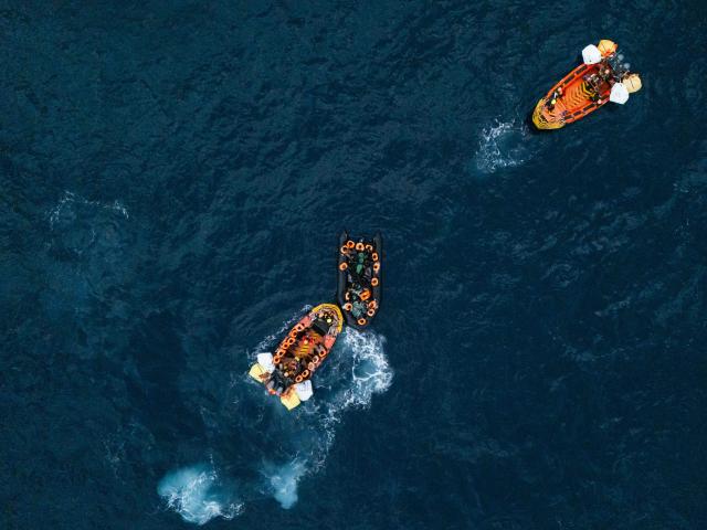 (FILES) This aerial photograph shows crew members of the “Ocean Viking” rescue ship rescuing a boat carrying migrants in destress using a RHIB (Rigid inflatable boat) in the search-and-rescue zone off the international waters of Libya on January 16, 2026. (Photo by Sameer Al-DOUMY / AFP)