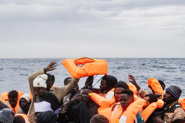 (FILES) Migrants onboard a rubber boat receive life jackets as crew members of the “Ocean Viking” rescue ship carry out a rescue operation using a RHIB (Rigid inflatable boat) in the search-and-rescue zone off the international waters of Libya, on January 16, 2026. (Photo by Sameer Al-DOUMY / AFP)