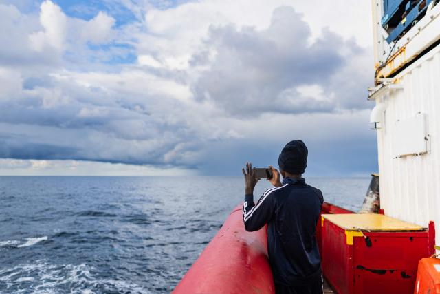 (FILES) A migrant takes a picture onboard the rescue ship "Ocean Viking" operated by the NGO SOS Mediterranee, in the search-and-rescue zone of the international waters near Malta, on January 1, 2026. (Photo by Sameer Al-DOUMY / AFP)