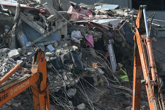 Rescue workers clear debris at the shopping mall in Karachi on January 23, 2026 following a massive fire that broke out on January 17. The death toll from a mall fire in Pakistan's biggest city rose to at least 67 people, an unnamed spokesperson from the local government said on January 23. (Photo by Rizwan TABASSUM / AFP)