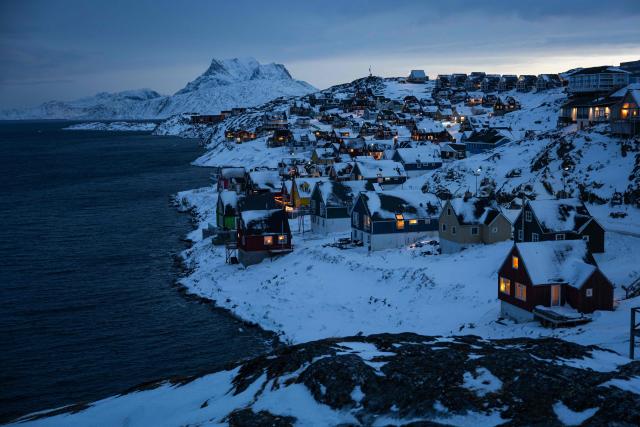 TOPSHOT - Houses along the coastline are lit as early morning light breaks over the snow-covered hills in Nuuk, Greenland, on January 22, 2026. (Photo by Jonathan NACKSTRAND / AFP)