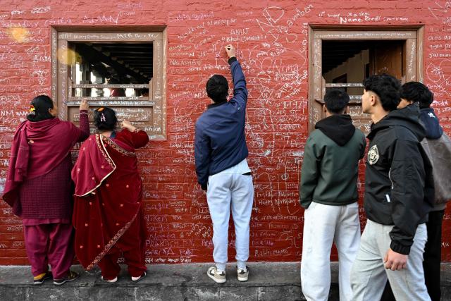 Devotees write messages with chalk on a wall at the Saraswati temple on the occasion of Hindu festival Basanta Panchami in Kathmandu on January 23, 2026. (Photo by PRAKASH MATHEMA / AFP)