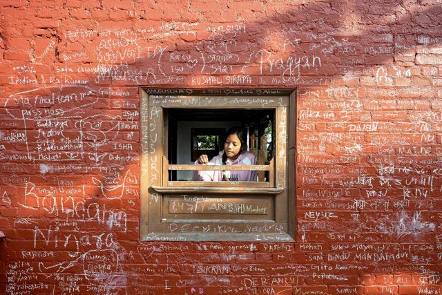 A girl writes a message with chalk on a wall at the Saraswati temple on the occasion of Hindu festival Basanta Panchami in Kathmandu on January 23, 2026. (Photo by PRAKASH MATHEMA / AFP)