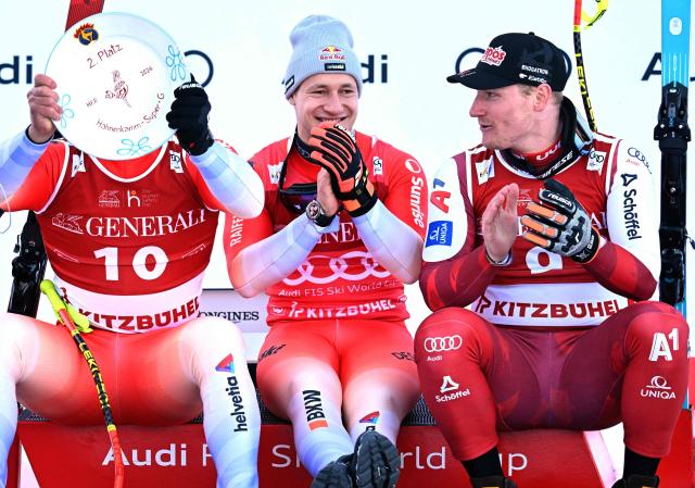(L-R) Second placed Switzerland's Franjo Von Allmen, winner Switzerland's Marco Odermatt and third placed Austria's Stefan Babinsky sit on the podium after the Men's Super-G event of the FIS Alpine Skiing World Cup in Kitzbuehel, Austria, on January 23, 2026 (Photo by BARBARA GINDL / APA / AFP) / Austria OUT