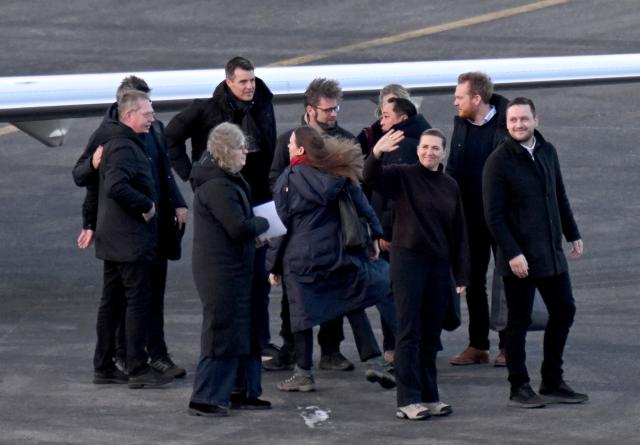 Danish Prime Minister Mette Frederiksen (2nd R) waves as she is welcomed by Greenland's Prime Minister Jens-Frederik Nielsen (R) after she landed at the airport in Nuuk, Greenland, on January 23, 2026. Frederiksen will hold talks with her Greenlandic counterpart after a turbulent week that saw US President Donald Trump back down from his threats to seize the Arctic island and agree to talks. Frederiksen travelled to the Greenland capital Nuuk from Brussels, where she held talks earlier with NATO Secretary General Mark Rutte, who reached a purported deal with Trump on Greenland at the World Economic Forum in Davos. (Photo by Jonathan Nackstrand / AFP)
