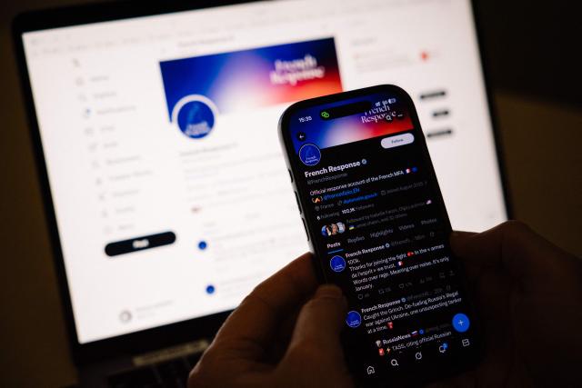 A photo shows a smartphone screen displaying the ‘French Response’ X account of the French Foreign Affairs Ministry, in Paris on January 23, 2026. Anti-MAGA punchlines, anti-Russia GIFs and tongue-in-cheek humour: with its ‘French response’ X account, the French Ministry of Foreign Affairs has equipped itself with a deliberately ironic tool to try to discourage France's adversaries in the information war. (Photo by Dimitar DILKOFF / AFP)