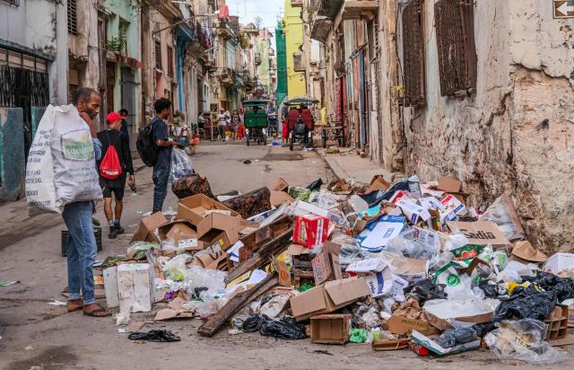 People walk by garbage discarded on a street in Havana on January 23, 2026. (Photo by YAMIL LAGE / AFP)