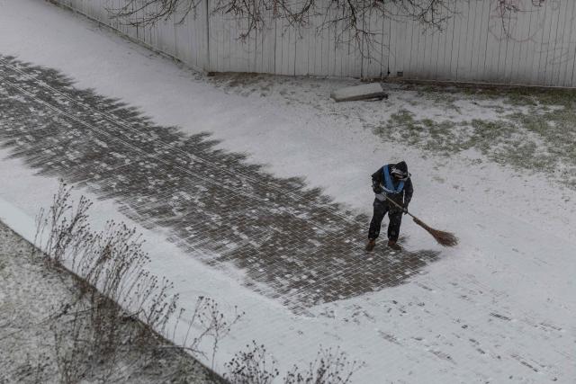 A worker clears snow from a sidewalk in Odesa on January 23, 2026, amid the Russian invasion in Ukraine. (Photo by Oleksandr GIMANOV / AFP)